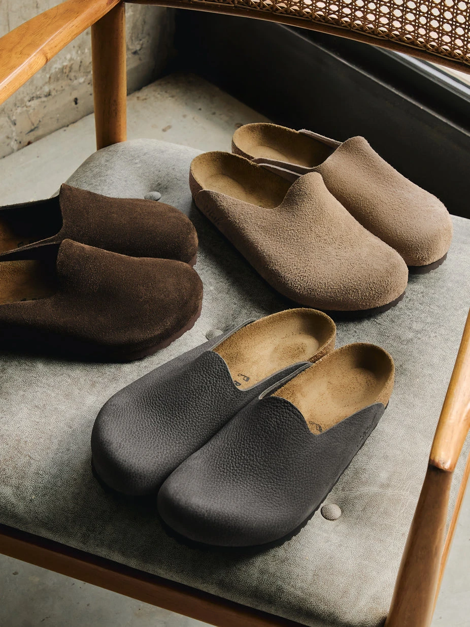 Amsterdam clogs in Mocca, Taupe, and Black arranged on a mid-century chair