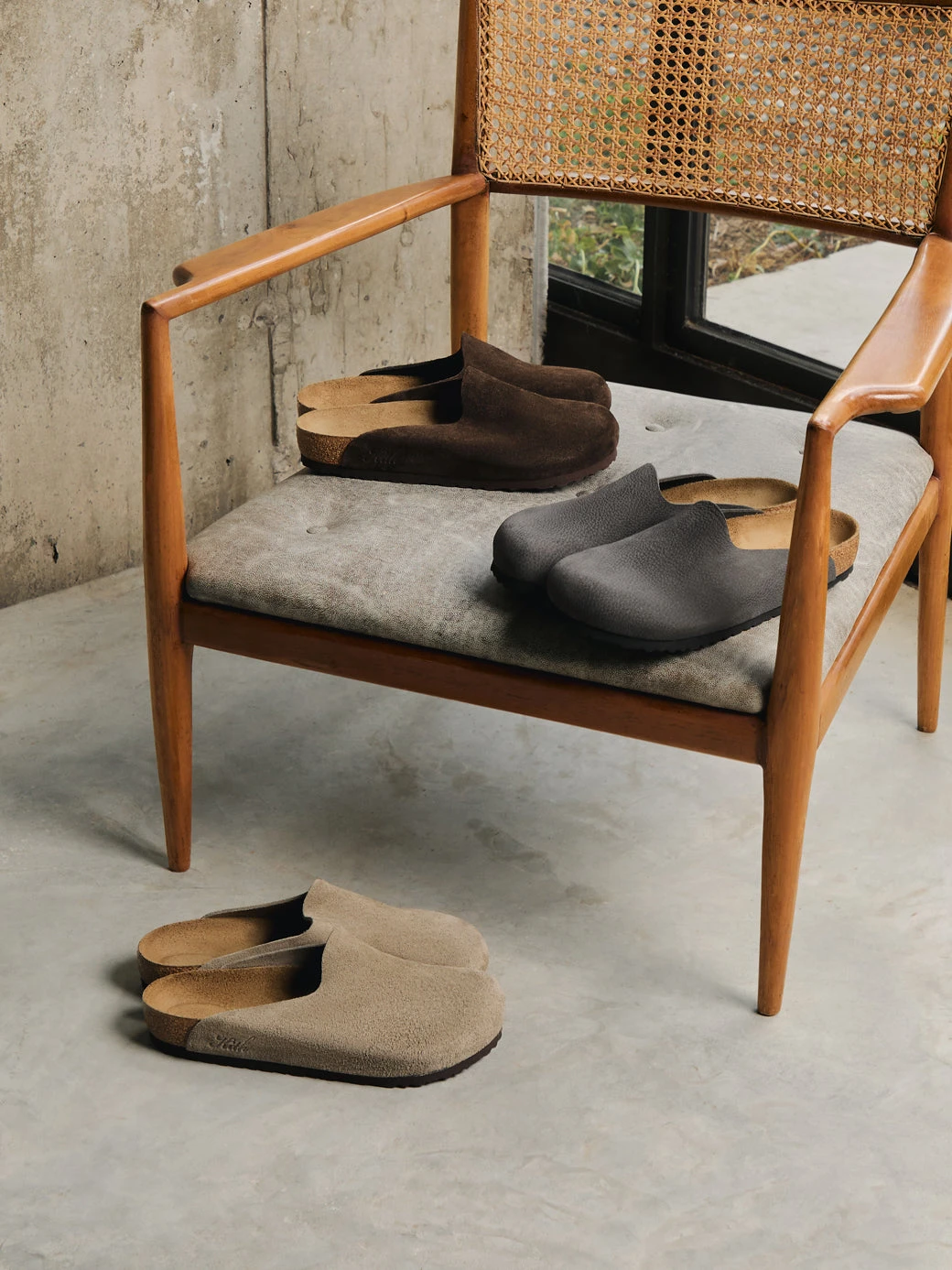 A cane-backed chair holding two Amsterdam clogs, a third pair on the floor