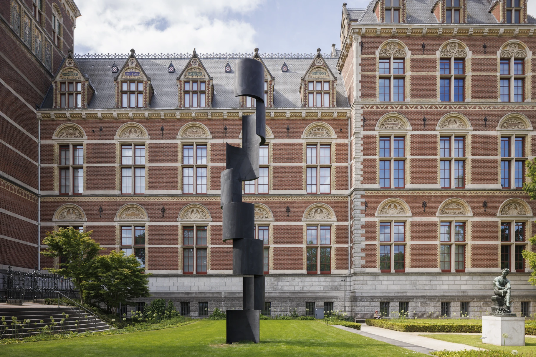 Carel Visser's black steel sculpture Jacobsladder standing on the lawn of the Rijksmuseum gardens with the museum facade behind